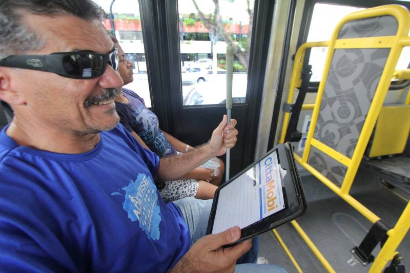 Pessoa com deficiência visual utilizando o ônibus e acessando o Cittamobi pelo tablet