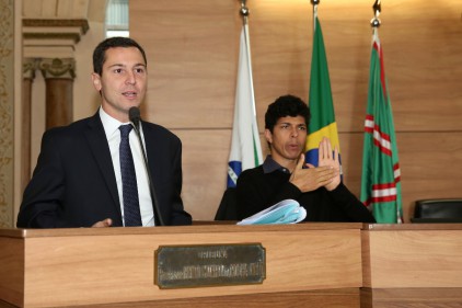 A imagem mostra um parlamentar da Câmara Municipal de Curitiba se pronunciando e o intérprete de Libras fazendo a tradução 