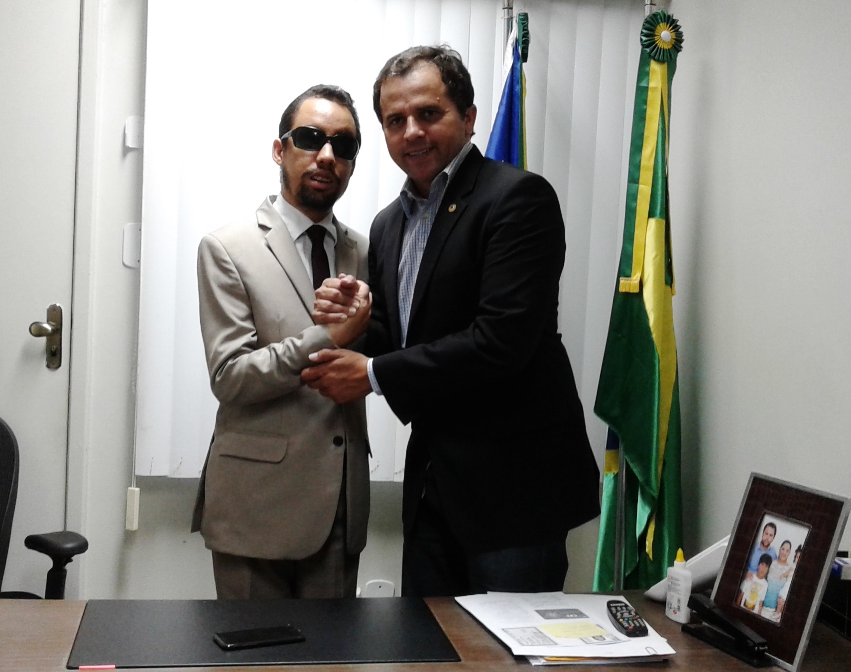 Vereador Lucas Aribé em pé apertando a mão do deputado Estadual Jairo de Glória