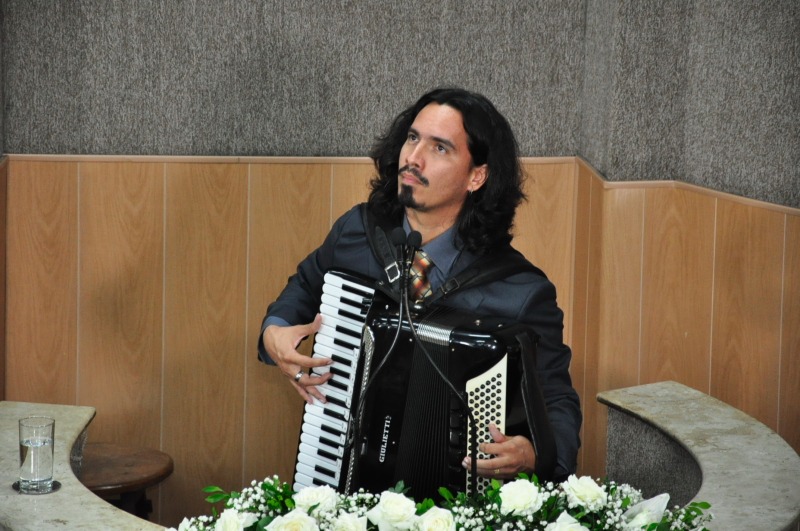 #PraCegoVer - Lucas Campelo, filho de Iara, toca sanfona em homenagem à mãe