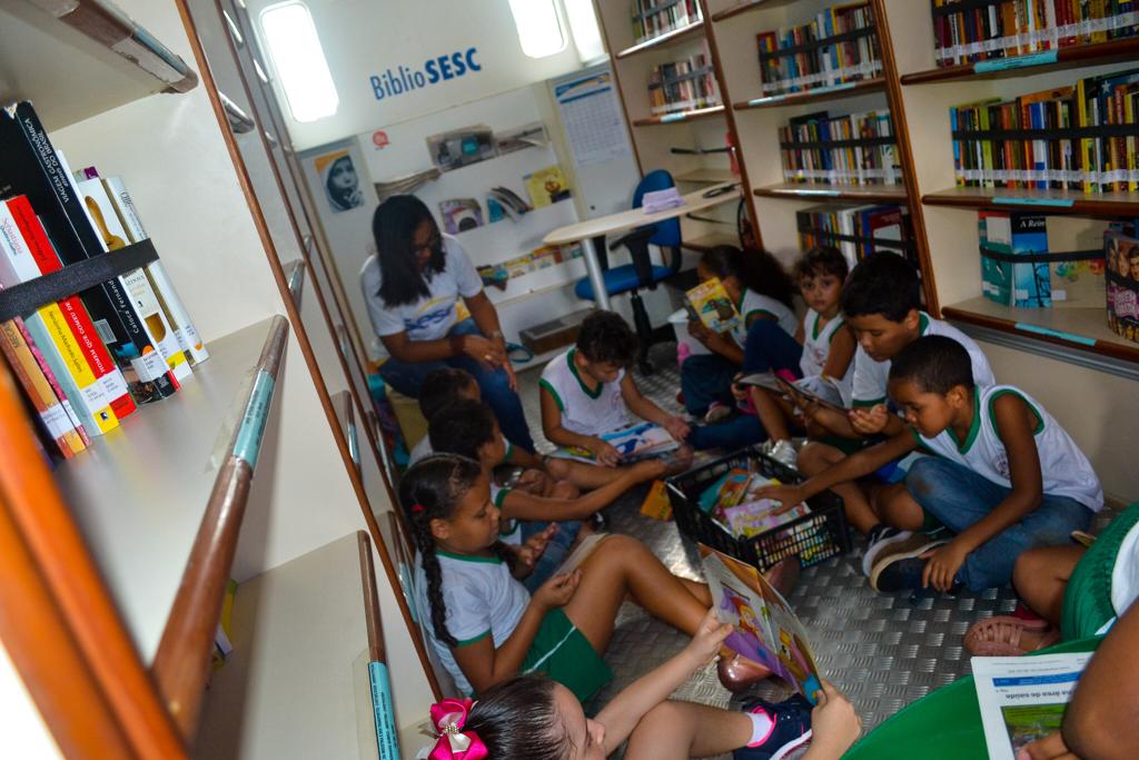 #PraTodoMundoVer Em ambiente interno, crianças sentadas no chão lendro livros