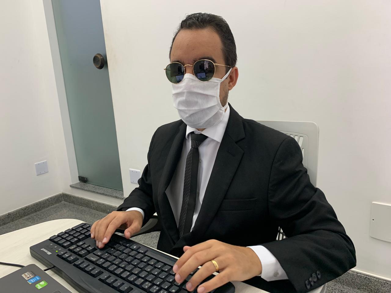 #PraTodoMundoVer Fotografia de Lucas Aribé. Ele usa terno preto, óculos escuros e uma máscara de proteção facial.